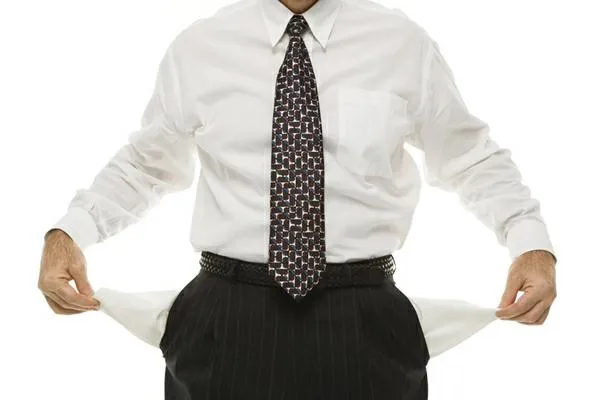 Caucasian middle-aged businessman pulling empty pockets out standing against white background.